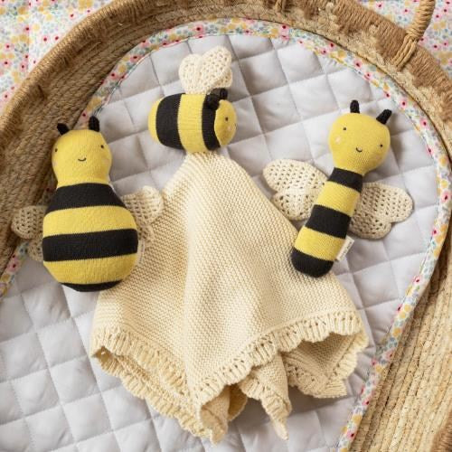 Knitted Avery Row bee toys and a blanket on a textured surface