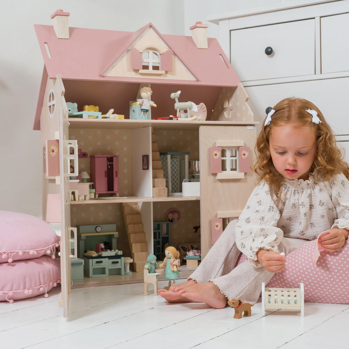 Young girl playing with a dollhouse in a bright room