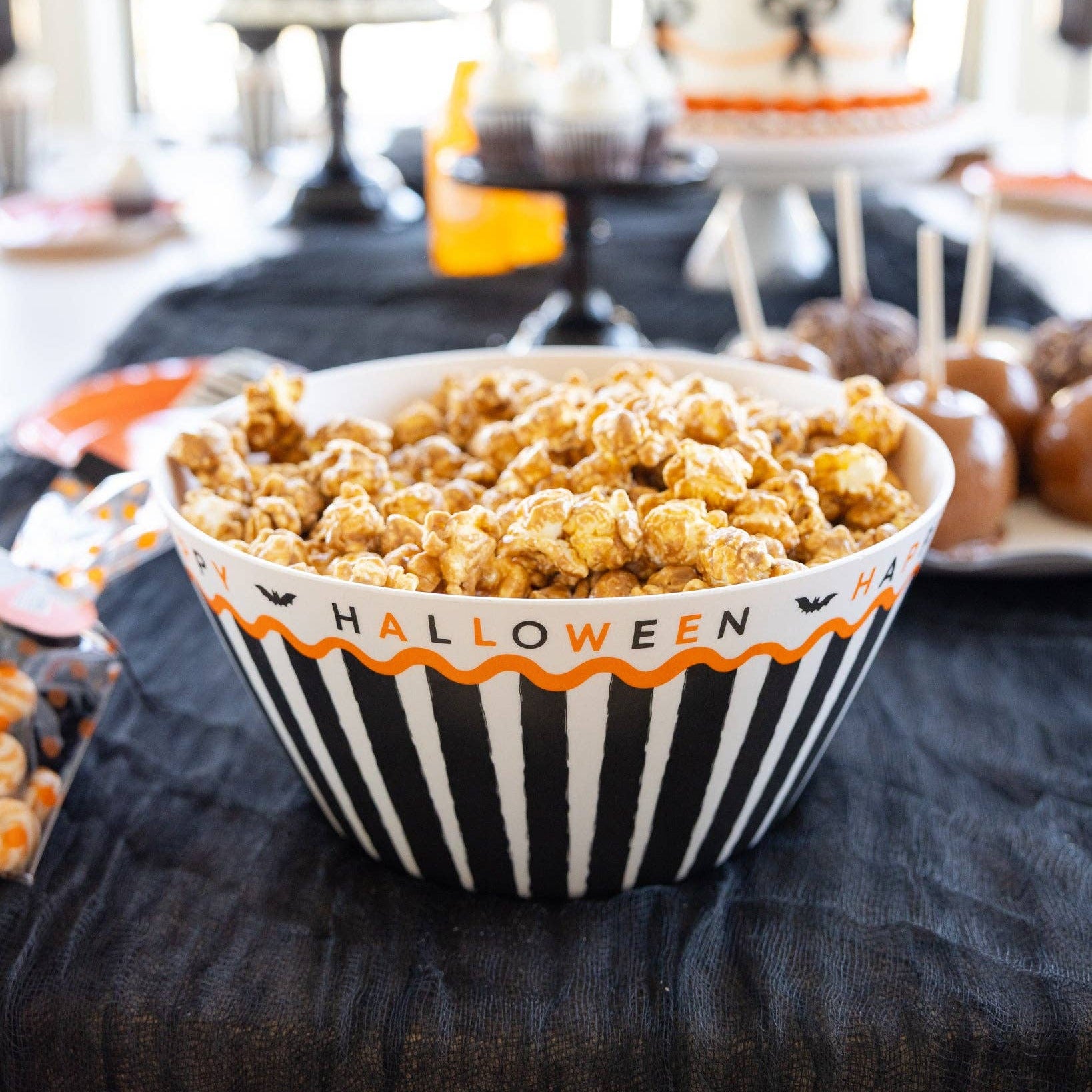 Halloween-themed bowl filled with popcorn on a table with festive decorations.