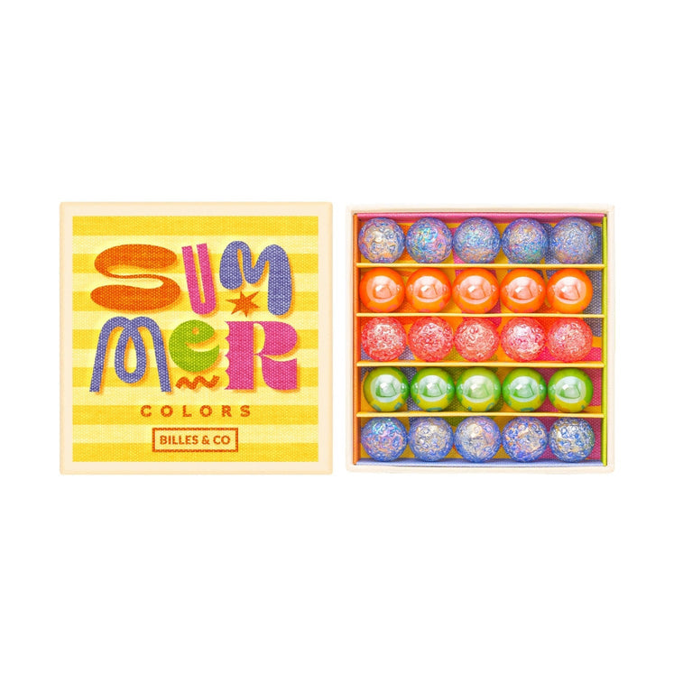 A colorful gift box of round candies or soap-like spheres, shown closed on the left and open on the right, revealing multiple pastel and bright round items inside. The box lid has the words 'Summer Colors' and 'Dilles & Co' on a yellow striped background.