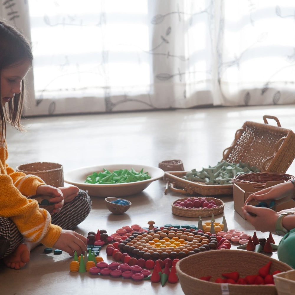 Two children playing with colorful toys on a wooden floor.