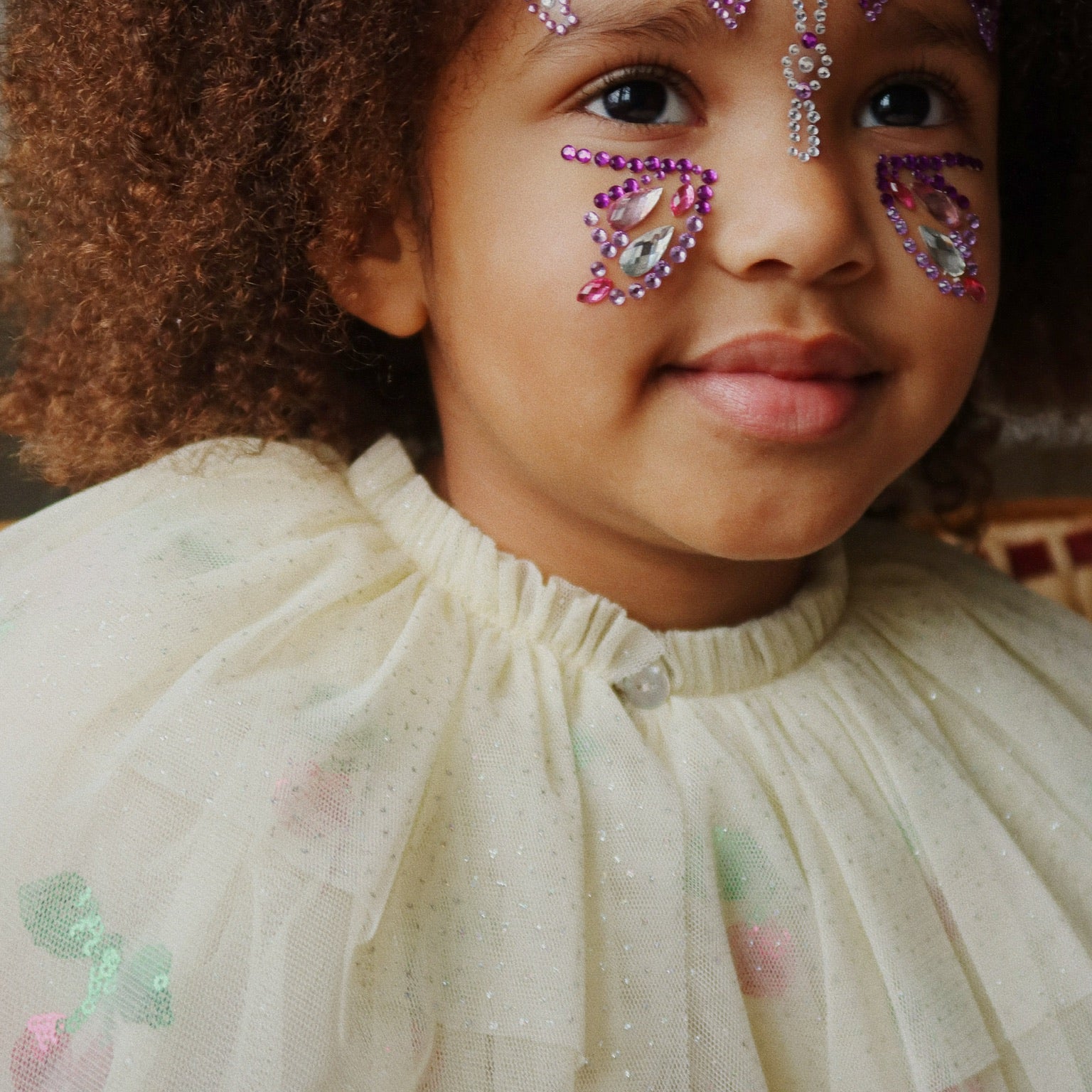 Child wearing decorative butterfly face paint with rhinestones