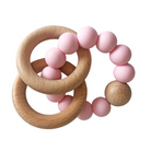 Pink baby teething rings with wooden elements on a white background