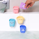 Colorful bath toy buckets hanging from a shower head with water flowing.
