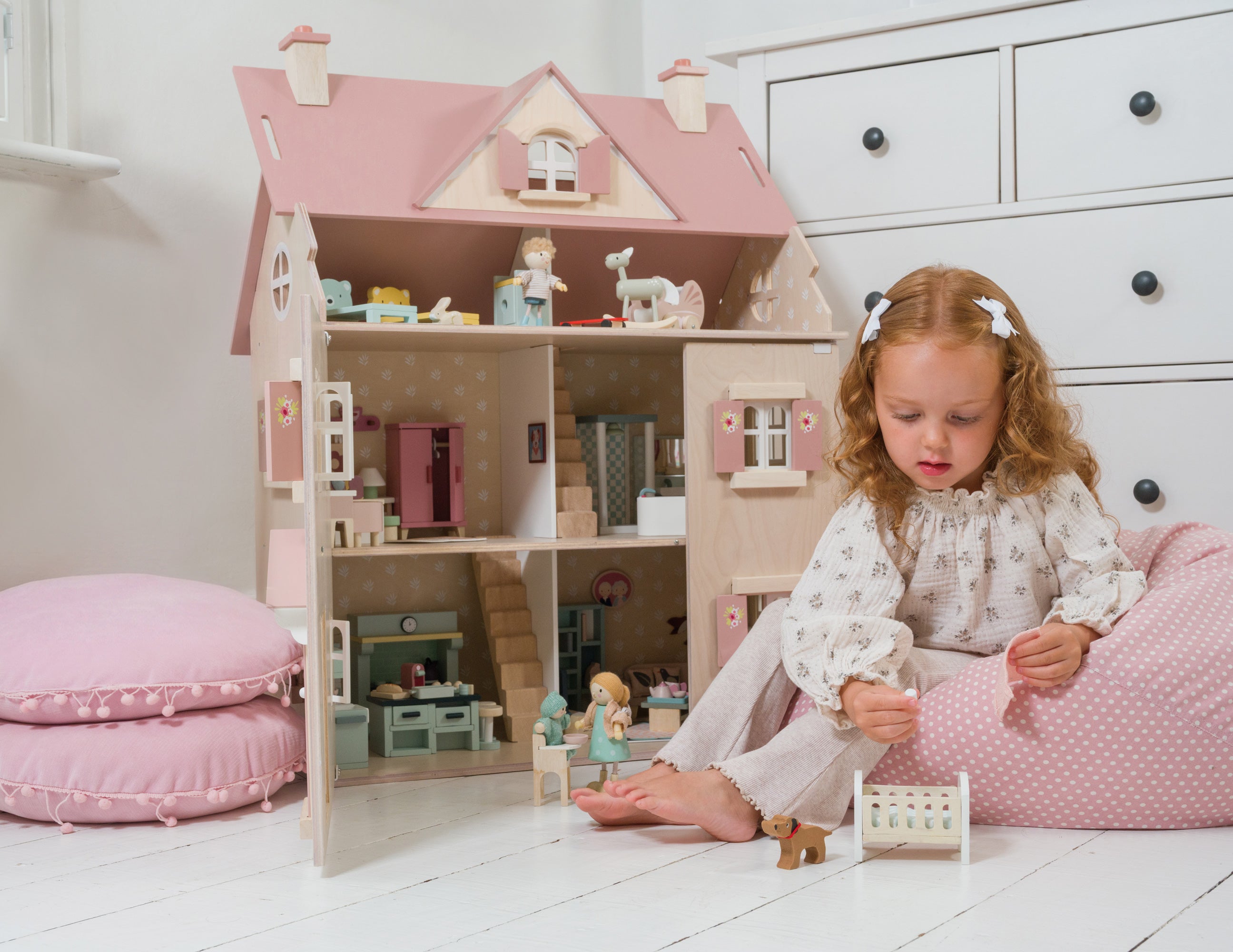 Young girl playing with a dollhouse in a bright room