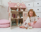 Young girl playing with a dollhouse in a bright room