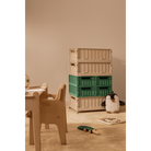 Children's room with wooden furniture, stacked crates, and toys on a beige floor.