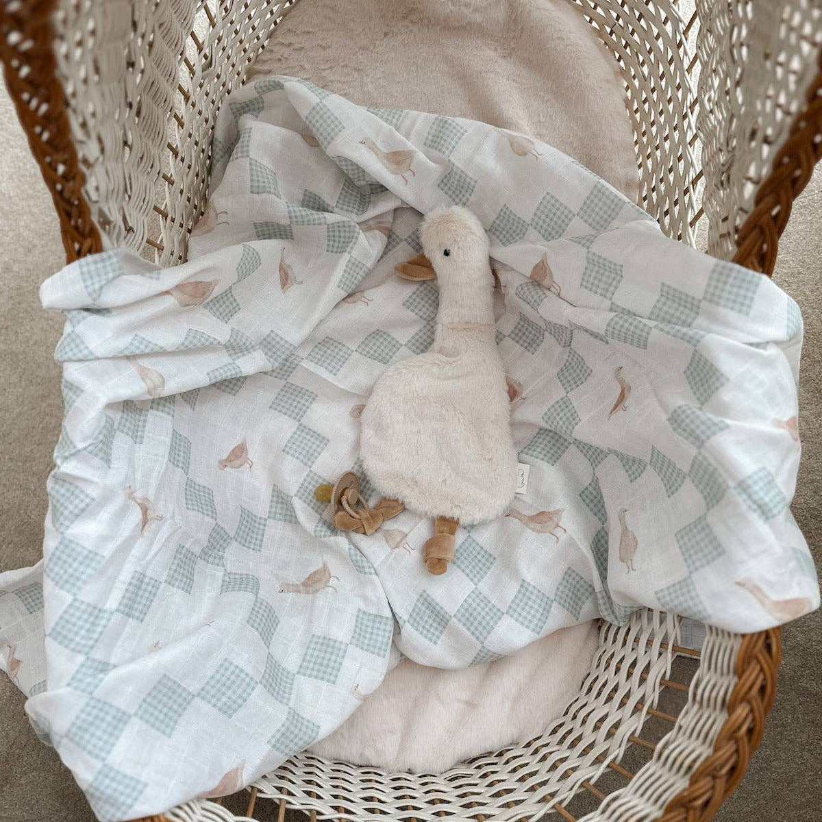 Baby swaddle with duck toy in a wicker basket