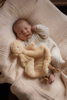Newborn baby sleeping with a plush duck comforter toy on a soft surface