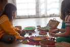 Two children playing with colorful toys on a wooden floor.