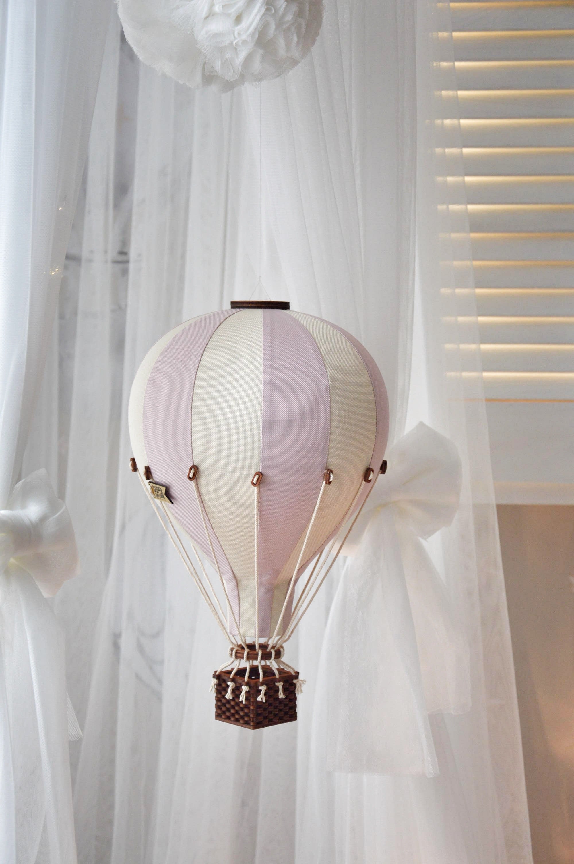 Decorative hot air balloon lamp hanging against a white curtain