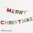 Reusable Meri Meri 'Merry Christmas' banner with metallic letters in red, green, gold, and silver, displayed on a clean white background with a 'REUSABLE' badge at the bottom.