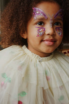 Child wearing decorative butterfly face paint with rhinestones