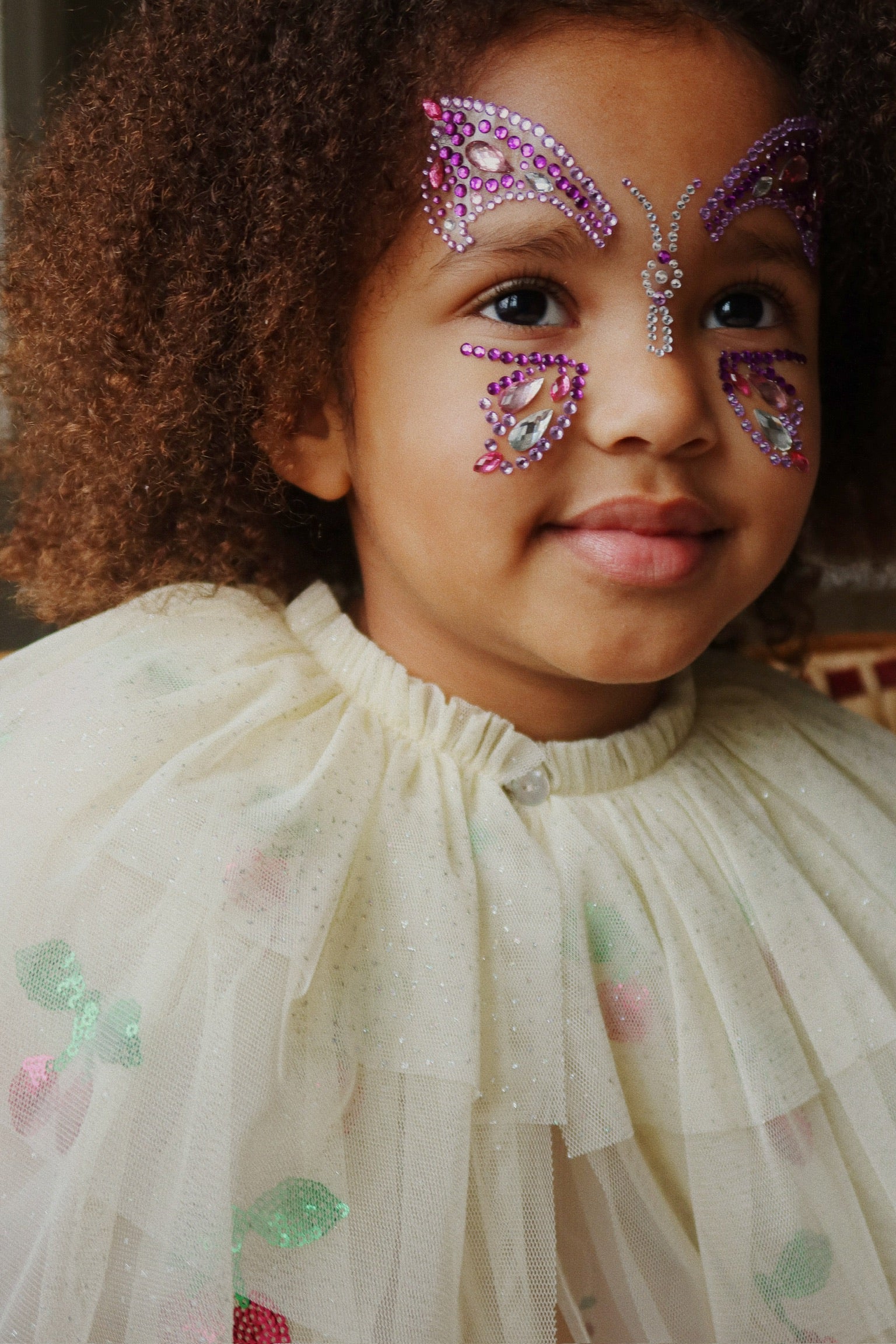 Child wearing decorative butterfly face paint with rhinestones