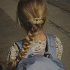 Person with braided hair wearing a gray backpack with swan designs.