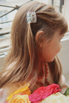 Child with floral hair clip and flower headband indoors