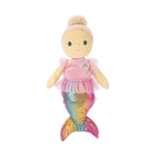 A mermaid-themed plush doll with a pale yellow face and hands, blonde hair in a bun, wearing a pink top with a small rainbow detail and a shimmering iridescent mermaid tail, isolated on a white background.
