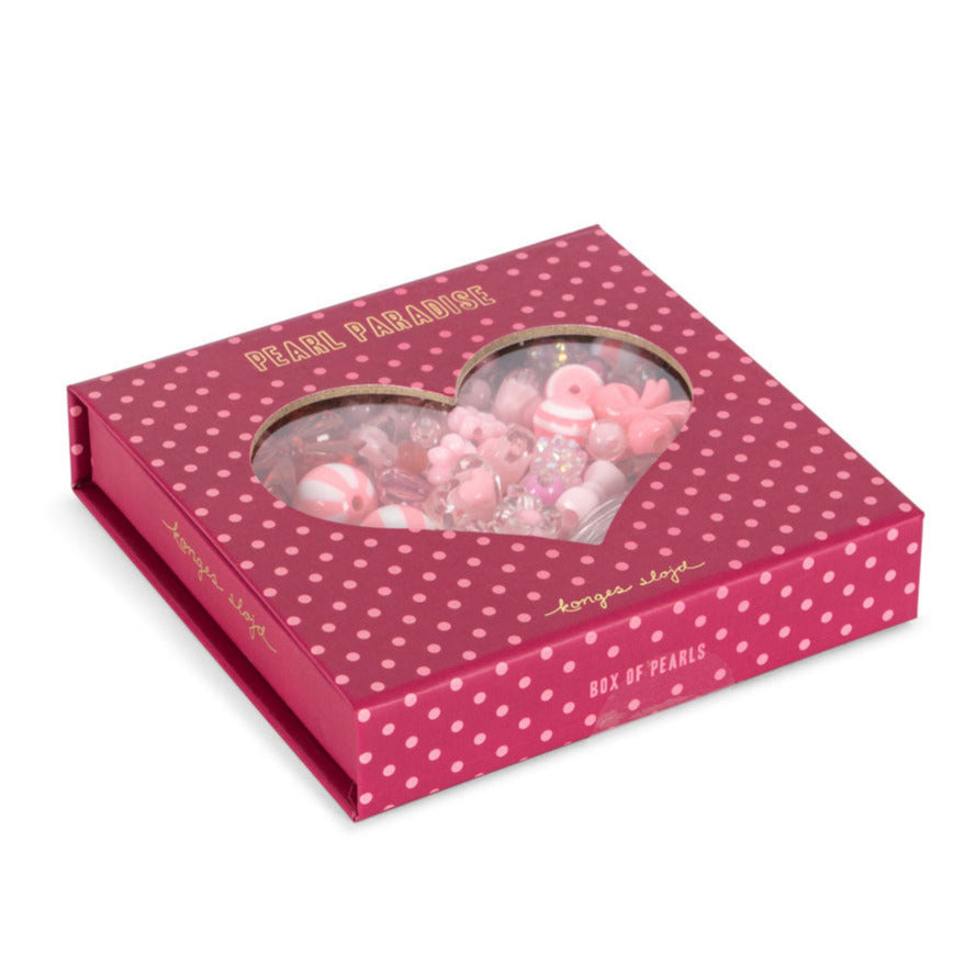 Pink polka dot box with heart-shaped window containing pink and white beads on a white background